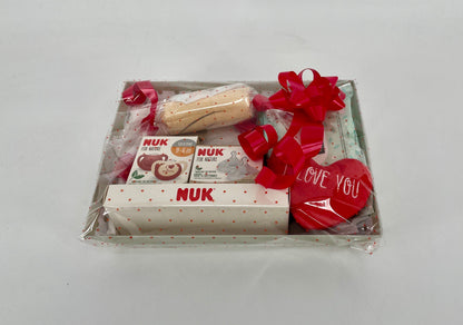 Canastilla de regalo MomentosGourmet para recién nacido con productos NUK, chupetes y corazón decorativo envuelta