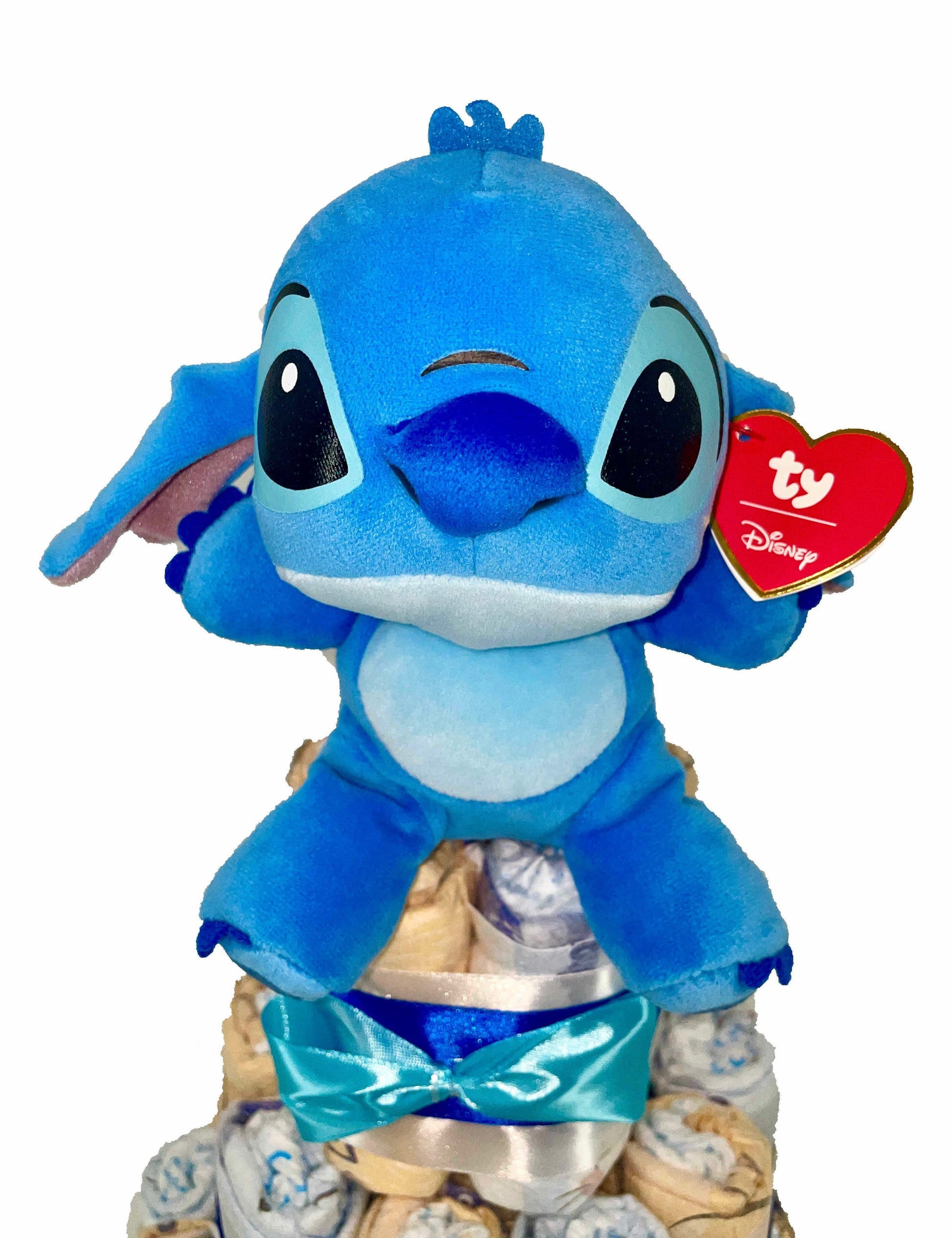 Tarta de pañales MomentosGourmet de tres niveles decorada con cintas azules y un peluche de Stitch de Disney